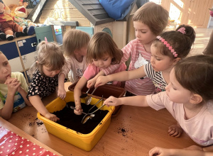 Dzieci wsypują ziemię do doniczki.