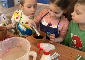 Dziewczynka wsypuje nasionka do ziemi.