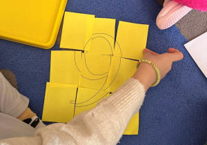 Dziewczynka dokłada fragment obrazka do układanki.