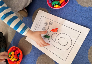 Chłopiec układa na konturach cyfry zwierzątka.