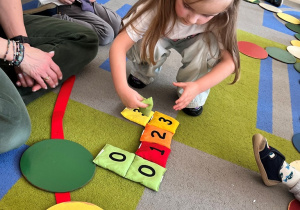 Dziewczynka dokłada swój woreczek z cyfrą do szeregu.