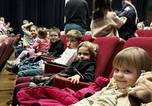 Dzieci siedzą na widowni w oczekiwaniu na spektakl.