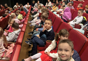 Dzieci siedzą na widowni w oczekiwaniu na spektakl.