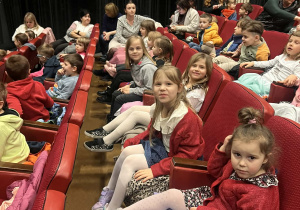 Dzieci siedzą na widowni w oczekiwaniu na spektakl.