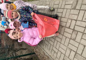 Dzieci w rękawiczkach i workiem do zbierania śmieci.