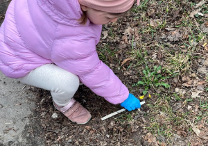 Dziewczynka podnosi smieć.