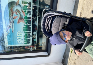 Chłopiec przed sklepem wędkarskim.