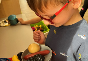 Chłopiec przygotowuje warzywa na patelni.