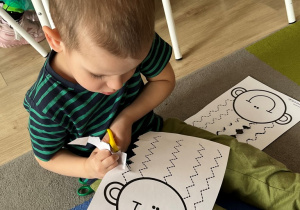 Chłopiec wycina nożyczkami.