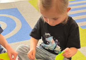 Dziewczynka w roli krawcowej, szyje.