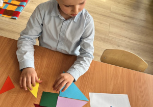 Chłopiec składa tangram według wzoru.