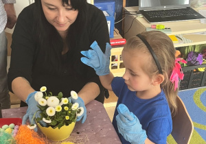 Mama z dziewczynką ozdabiają doniczkę.