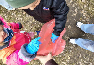 Dzieci wkładają śmieci do worka.