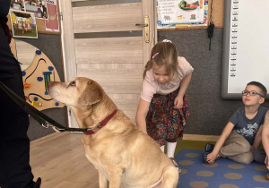 Dziecko głaszcze pieska.