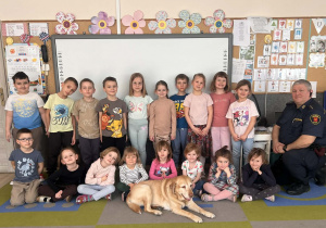 Dzieci i Strażnik pozują do zdjęcia z pieskiem.