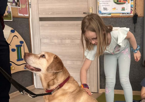 Dziecko głaszcze pieska.