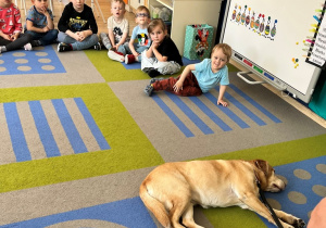 Dzieci obserwują leżącego psa.