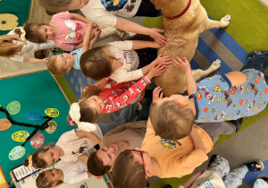 Dzieci głaszczą psa na pożegnanie.