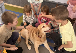 Dzieci głaszczą psa.