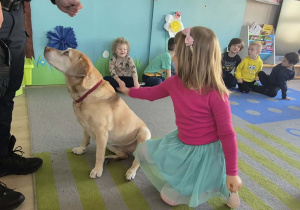 Dziewczynka głaszcze psa.