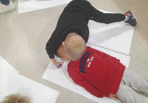 Dziecko odrysowuje swojego kolegę.