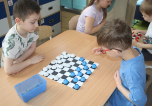 Dzieci rozgrywają mecz warcabowy.