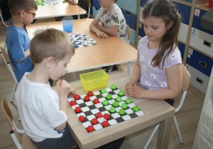 Dzieci rozgrywają mecz warcabowy.