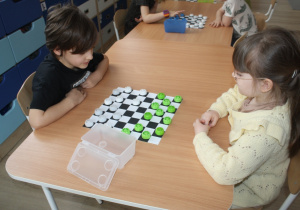 Dzieci rozgrywają mecz warcabowy.