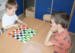 Dzieci rozgrywają mecz warcabowy.