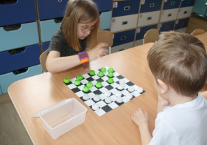 Dzieci rozgrywają mecz warcabowy.