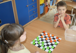 Dzieci rozgrywają mecz warcabowy.