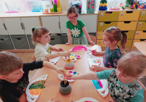 Dzieci malują farbami.