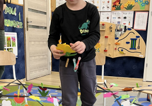 Chłopiec przechodzi przez pajęczyne i zbiera żółte kwiatki.