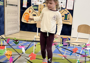 Dziewczynka w pajęczynie z pomarańczowym kwiatkiem.