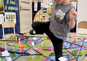 Chłopiec podnosi nogę, by pokonać taśmę.