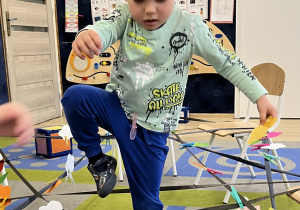 Chłopiec unosi nogę i pokonuje przeszkodę.