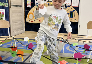 Chłopiec z białym kwiatkiem pokonuje pajęczynę.