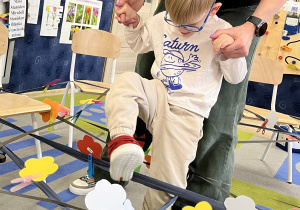 chłopiec z pomocą nauczycielki pokonuje pajęczynę.