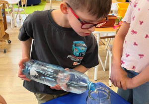 Chłopiec wlewa wodę do słoika.