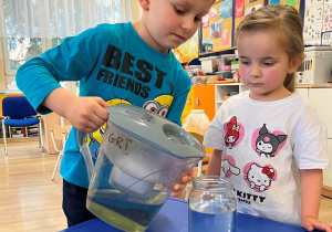 Dzieci wlewają wodę do słoika.