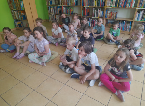 Dzieci siedzą na poduszkach w bibliotece
