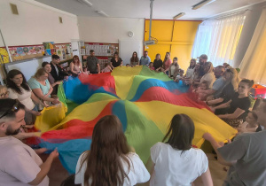 Dzieci i rodzice tańczą z chustą animacyjną.