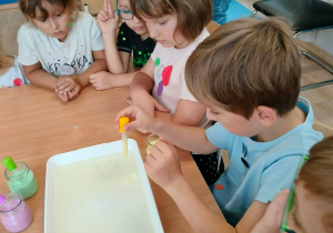 Dzieci nakładają pipetkami barwniki.