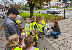 Nauczycielka tłumaczy dzieciom zasady przechodzenia przez ulicę.