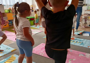 Dzieci stoją na jednej nodze.