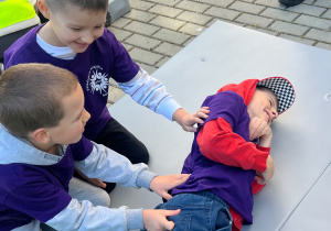 Dzieci układają chłopca w pozycji bezpiecznej.