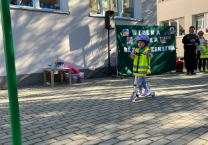 Dziewczynka jedzie na hulajnodze.