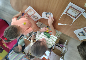 Dzieci wycinają nożyczkami.