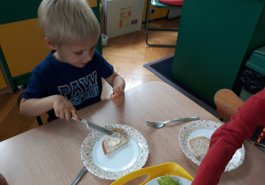 Chłopiec smaruje kromkę chleba masłem
