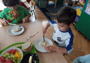 Dzieci smarują kromki chleba masłem